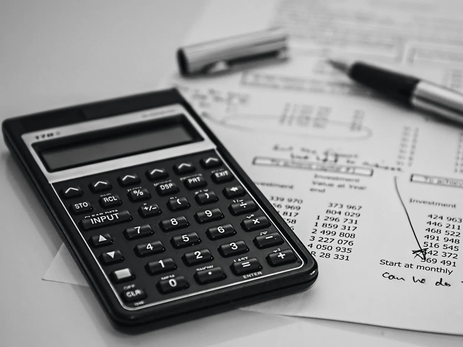 A calculator and pen on a printed sheet of figures