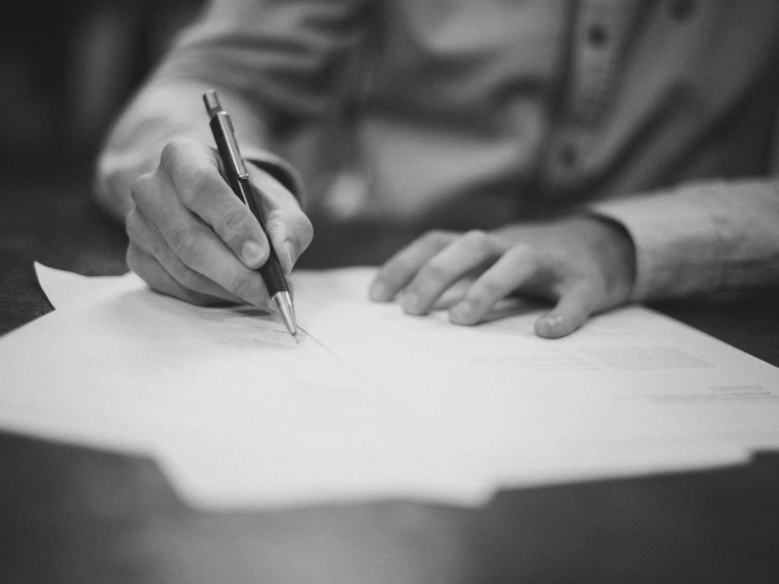 A hand signing a document