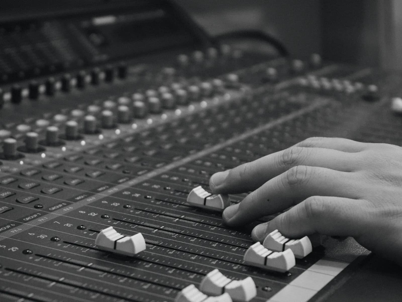 Hands on the faders of a mixing desk